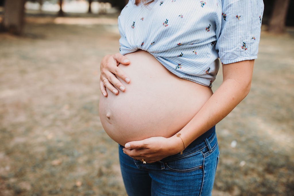 Eine Schwangere hält ihren Bauch, sie ist ca im 8. Monat